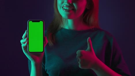 woman showing phone with green screen and thumbs up