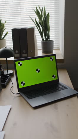 Laptop with Green Screen Display on Office Desk