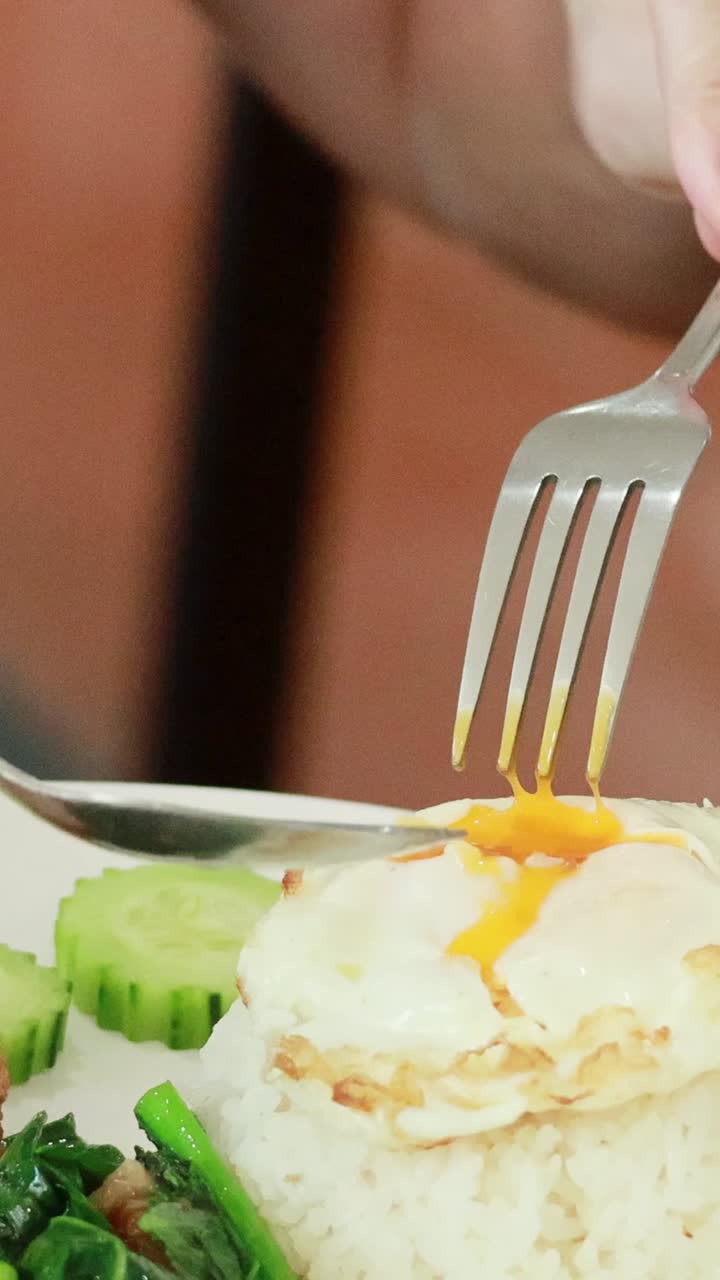 Jedení rýže, vejce a zeleniny pomocí příborů.