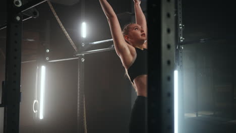 sportswoman is doing exercises on crossbar in sports hall healthy lifestyle and keeping fit