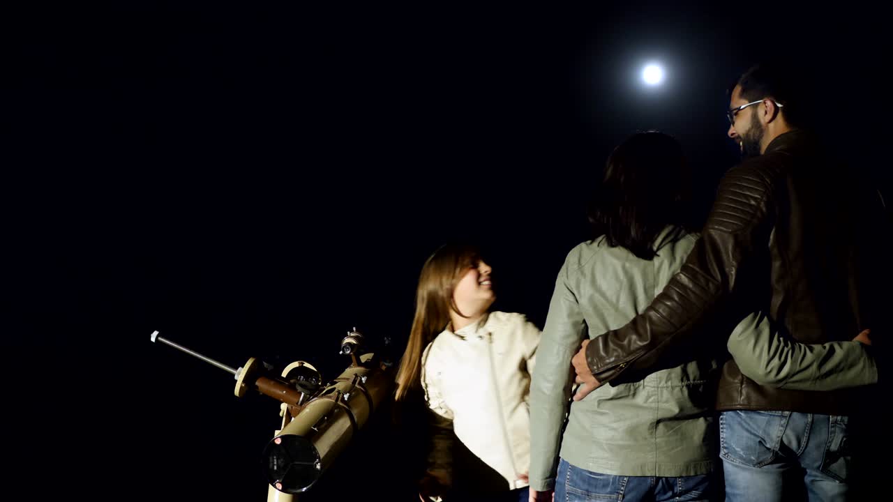 familia feliz observando la luna en un telescopio por la noche