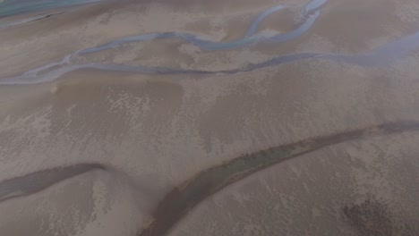 aerial drone fly rivers through sand black glacial icelandic soil textured earth