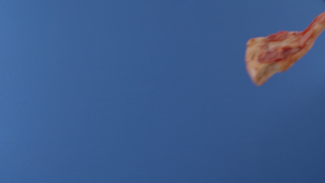 se ve una porción de pizza volando de un lado a otro frente a una pantalla azul