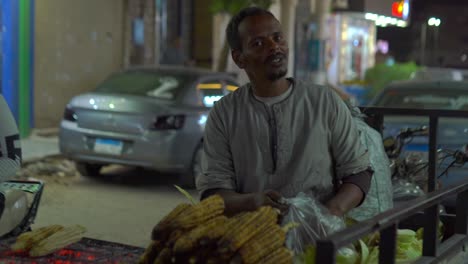 happy man is selling corn on the evening street