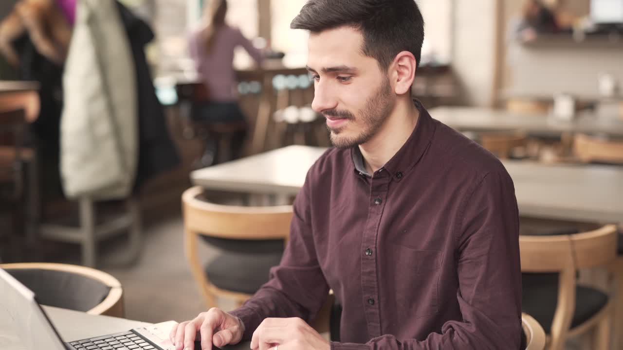 un hombre guapo con una camisa burdeos se sienta en el restaurante