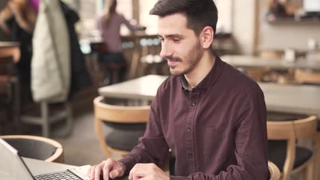 a handsome man in a burgundy shirt sits in the restaurant