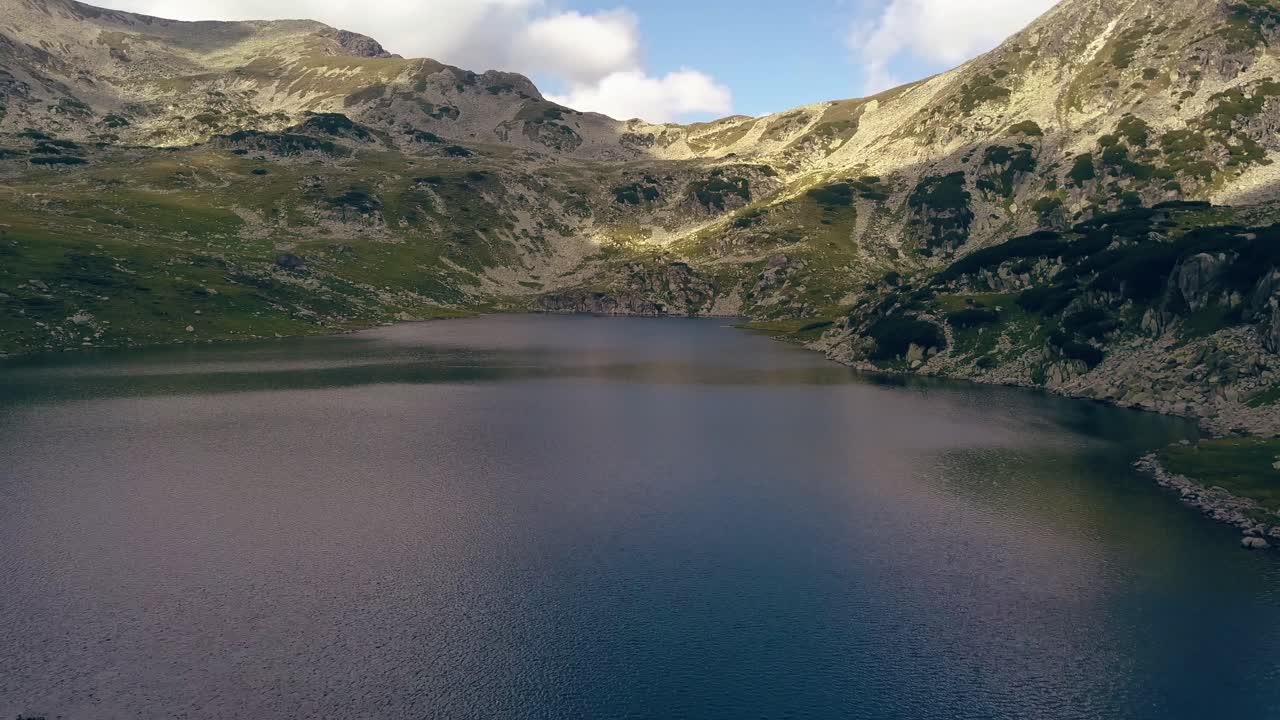 gran dron aéreo volando lentamente sobre un lago hacia una cordillera