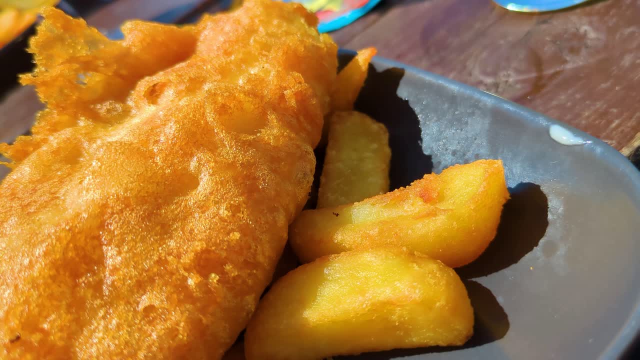 Close Up Details of Battered Classic Rustic British Fish and Chips Outside During Summer Time. Traditional Fast Food Cuisine.