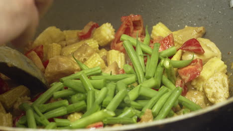 agregando judías verdes frescas al delicioso curry de pollo tailandés cocinado en un wok