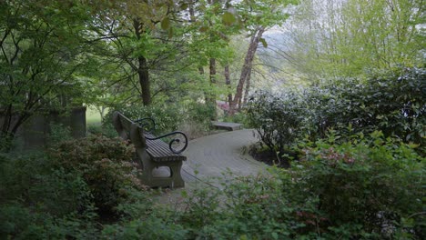 Picturesque-bench-next-to-cobblestone-path-surrounded-by-vegetation-in-Coal-Harbour-park-area,-Vancouver,-British-Columbia,-Canada