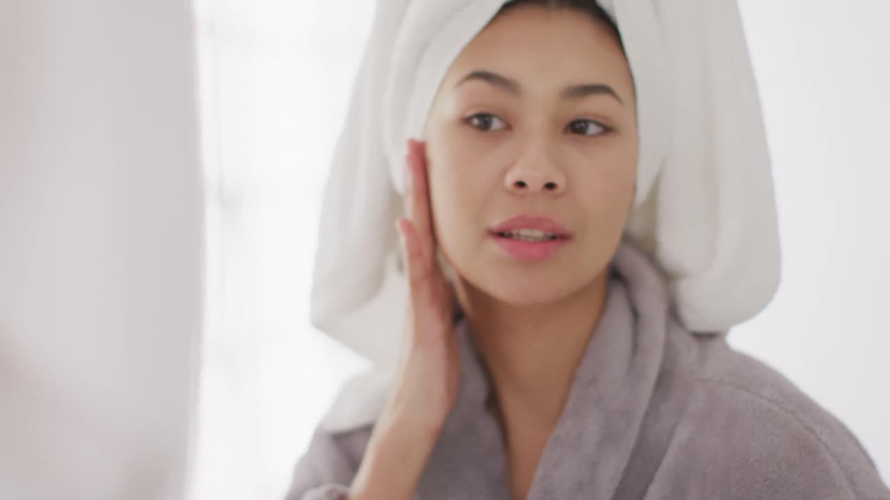 화장실 에서 거울 을 바라보는 머리카락 에 수건 을 쓴 미소 짓는 두 인종 의 여성 의 초상화 의 비디오