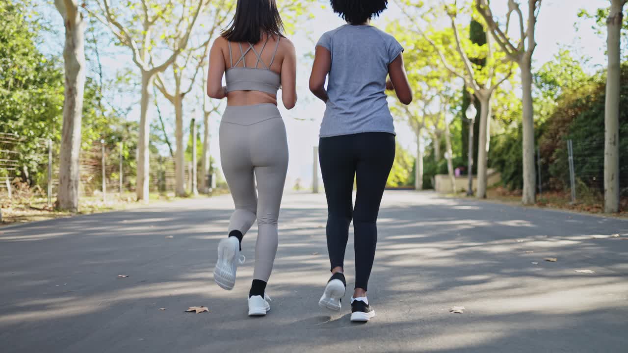 Due donne che corrono insieme su un sentiero in un parco soleggiato