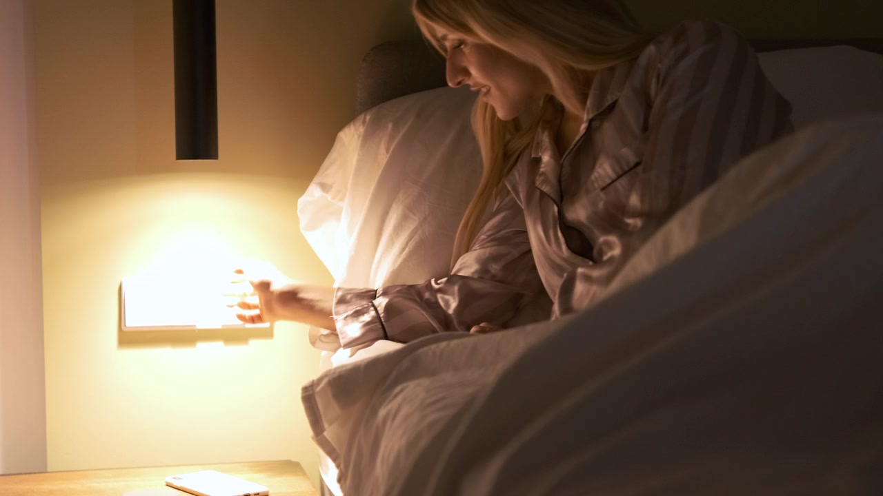Young Woman Turning Off Bedside Lamp Before Sleeping