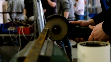 worker sawing metal bar of angular grinding machine.