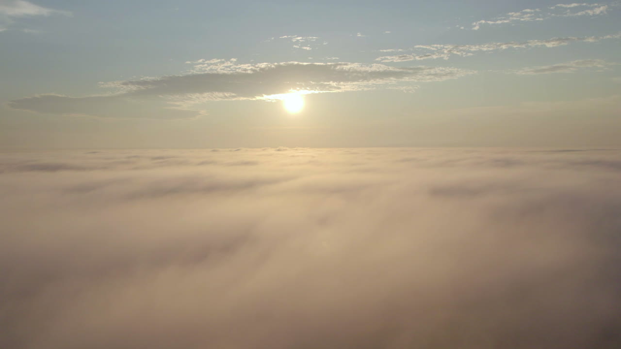 Cinematic drone shot above the clouds into the sun