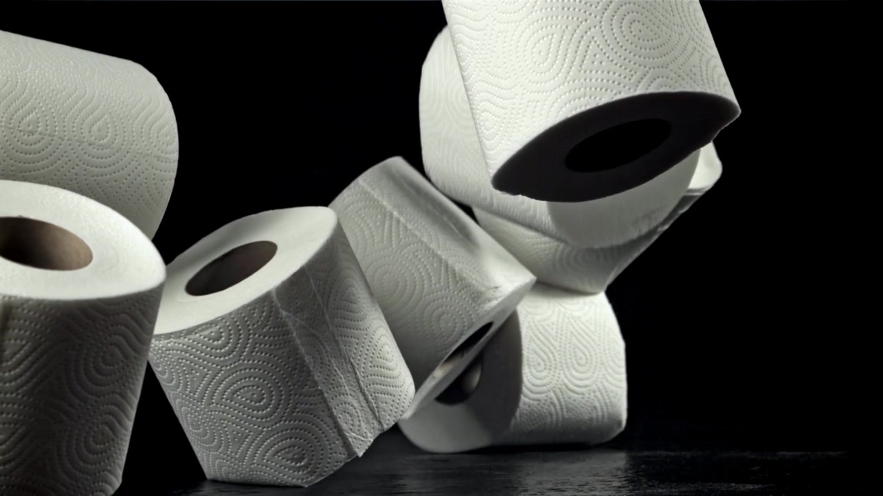 White Toilet Paper Rolls Falling in Slow Motion Against Black Background