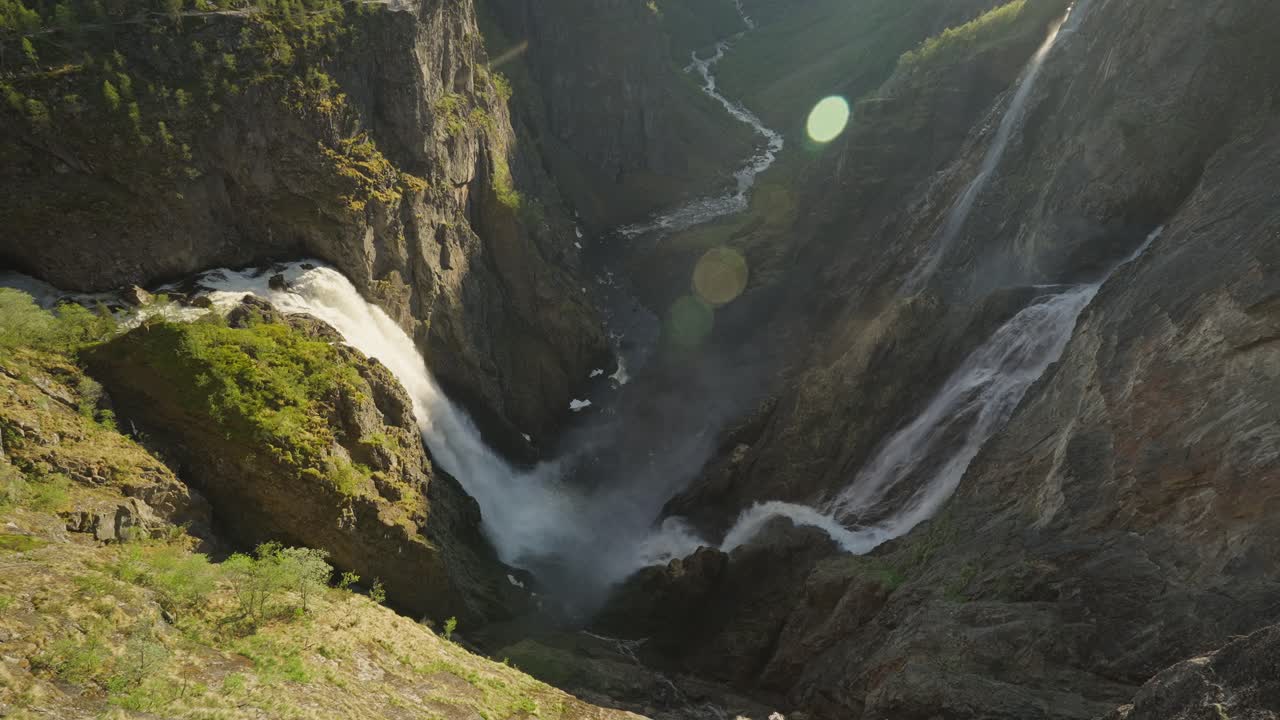 Voringsfossen waterfall in Norway cascading down steep cliffs with sunlight reflecting off mist