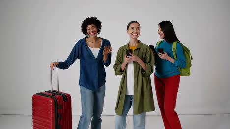 happy young women friends with luggage and smartphones ready for a trip
