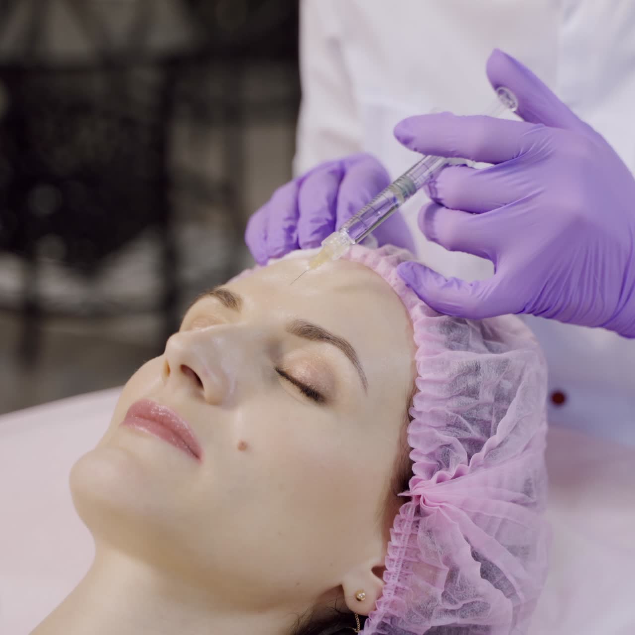 A beautiful woman is on the procedure of facial rejuvenation. Beautician makes mesotherapy of the forehead area. Beauty injections