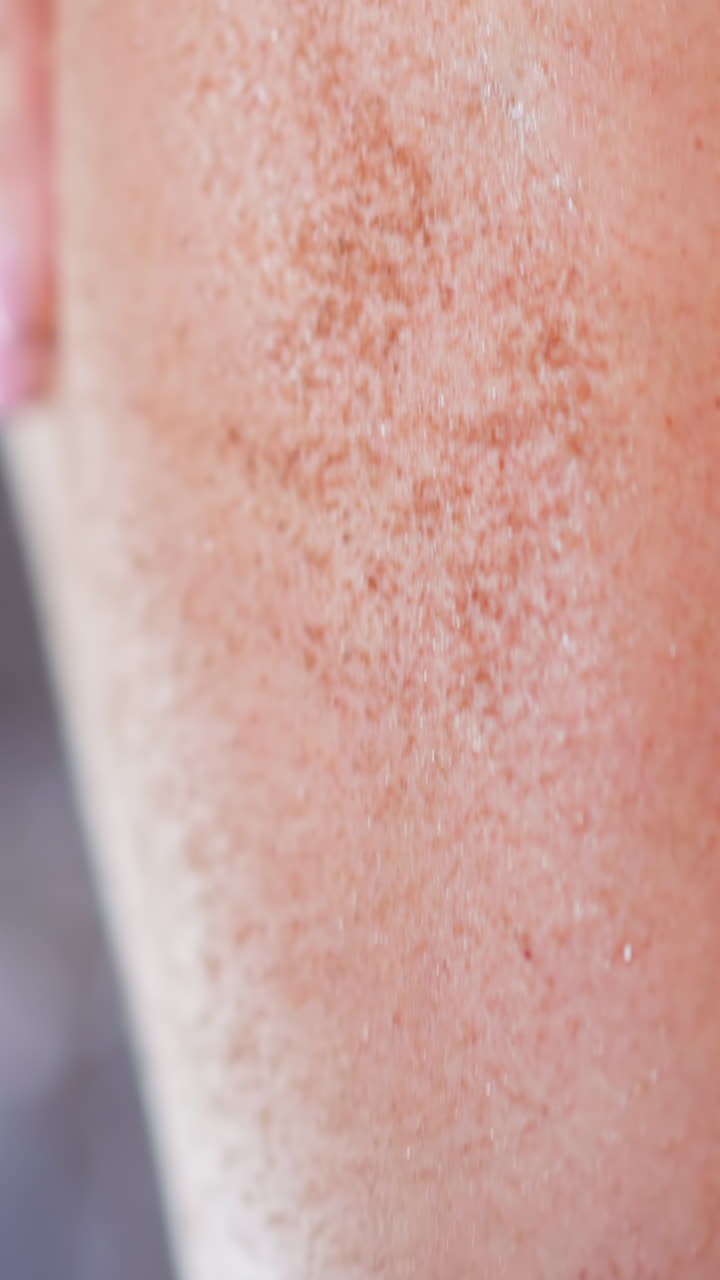 Young woman makes anti-cellulite massage on thigh spreading coffee scrub in circular moves with palm at home body care routine extreme closeup