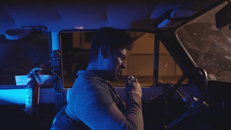 Young-teen-driver-drinking-in-vintage-car-while-pulled-over-by-police-at-night-in-4K