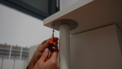 detail shot of male hands failing to screw a table leg with small screwdriver