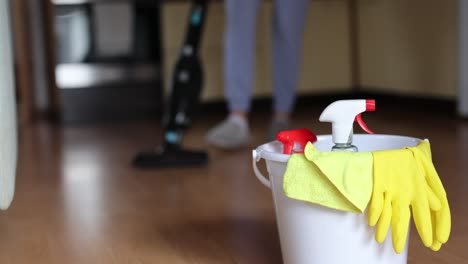 4k video footage detergents in a bucket on the floor and woman cleaning her home in the background