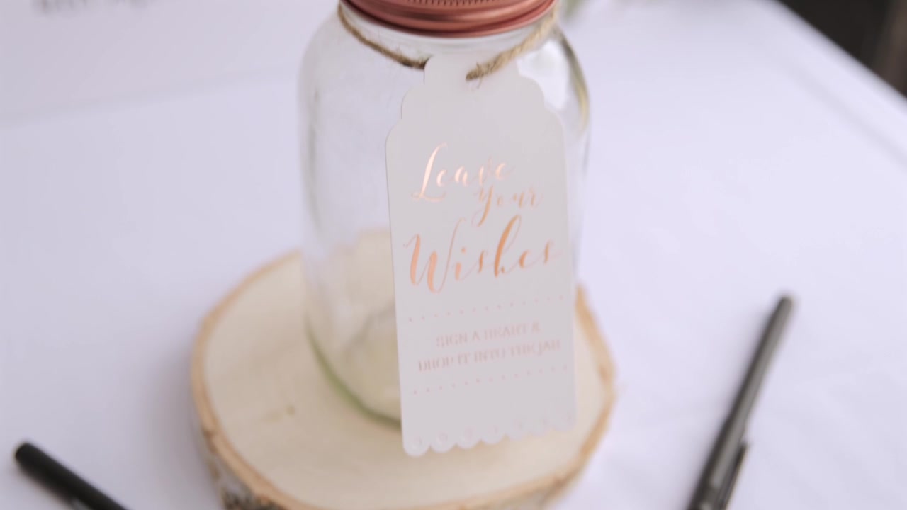 Primo piano a mano libera di un barattolo per gli auguri di matrimonio con penne e cuori di legno