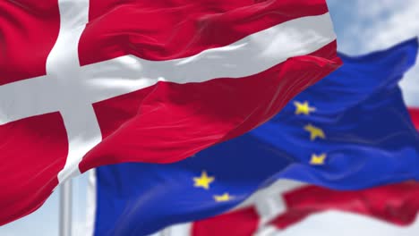 detail of the national flag of denmark waving in the wind with blurred european union flag in the background on a clear day