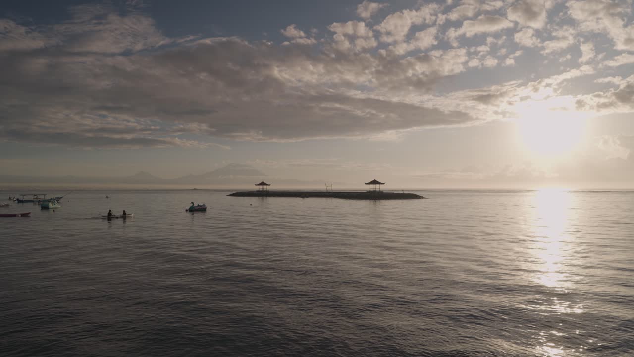 Sunrise over the ocean in Bali, with boats and kayakers