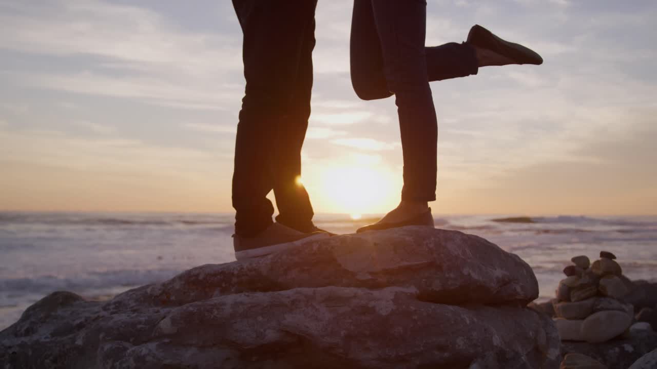 바다 근처의 바위 위에 서 있는 부부