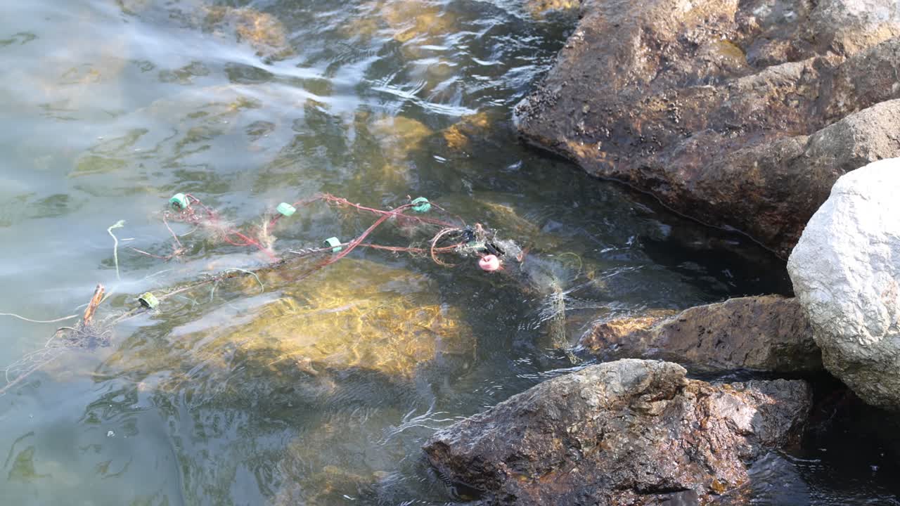 Old fishing net tangled among coastal rocks.
