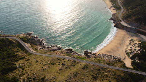 Küstenlandschaft-Mit-Strand-Und-Straße,-Sonnenstrahlen-Spiegeln-Sich-Im-Meer