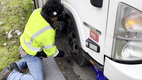 Hispanic-man-changing-the-tire-of-a-trailer-stranded-on-the-road