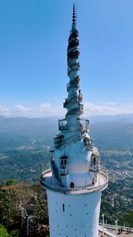 ambuluwawa trigonometrical station in sri lanka. lots of tourists stand on the stairs on top. revealing view of the stunning scenery at backdrop. vertical video.