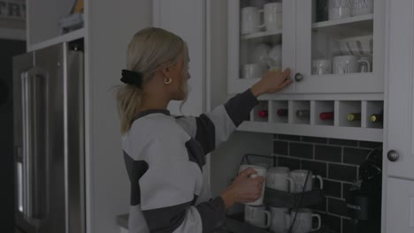 Eine-Frau-Geht-An-Einen-Schrank,-Um-Sich-Eine-Tasse-Kaffee-Zu-Holen