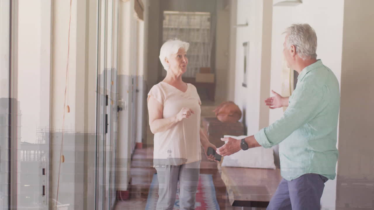 Dancing joyfully, elderly couple in bright hallway at home enjoying animation