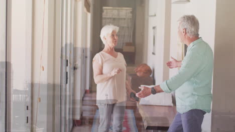 dancing joyfully, elderly couple in bright hallway at home enjoying animation