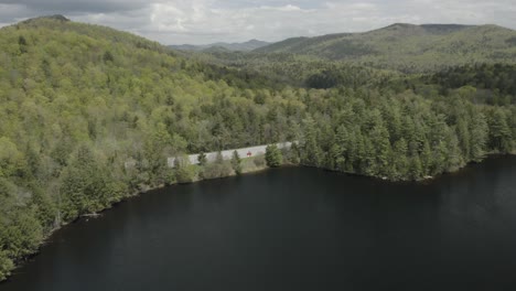 scenic view of a lake and forested mountains with a winding road