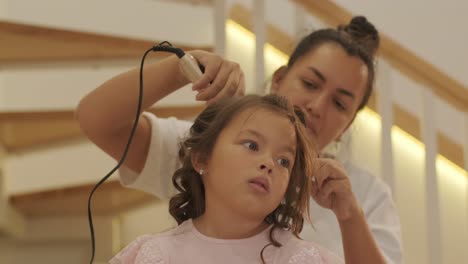 pregnant mother styling her daughter's hair at home