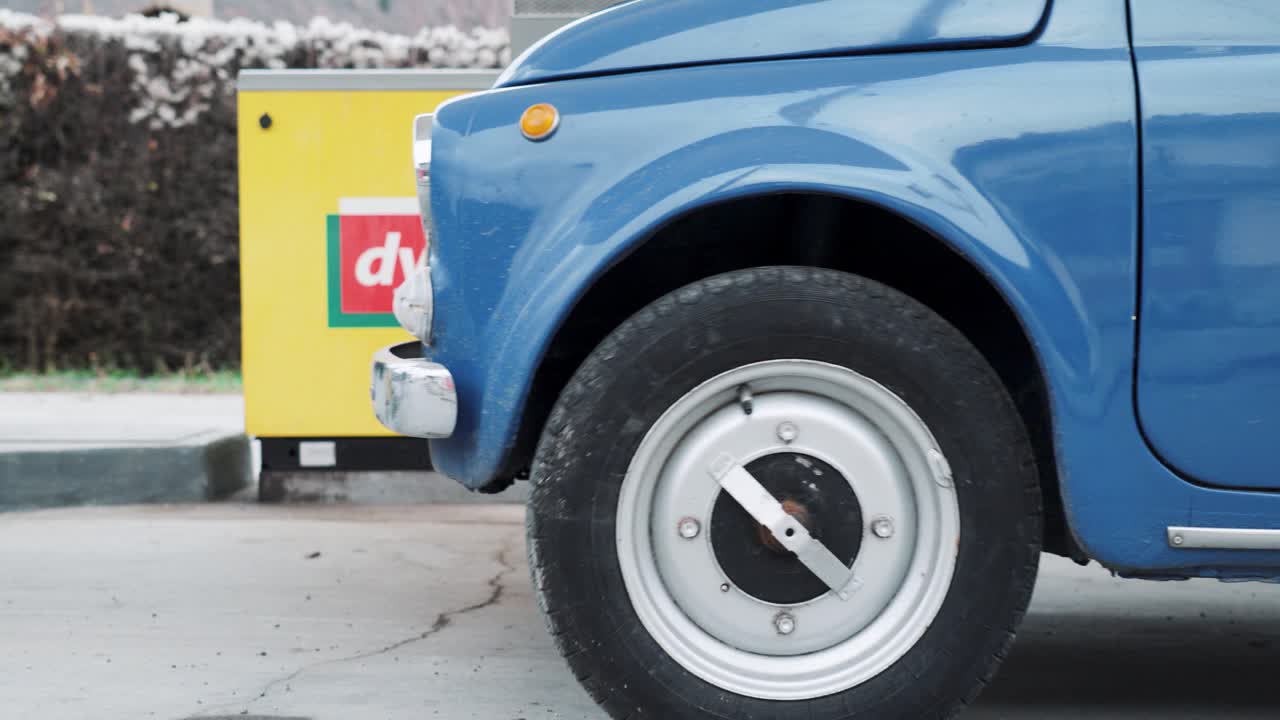 Fiat 500 vintage car pulls up to petrol filling station