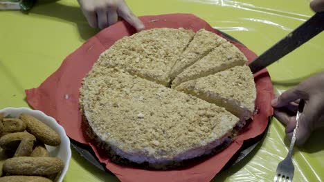 mom cuts a cake with a big knife, which stands on a red napkin on a yellow tablecloth. family celebration. close up. the view from the top. 4k.