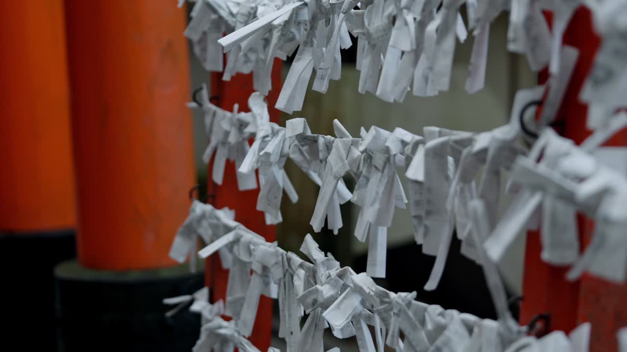 Wishing papers flutter gently in the breeze at Fushimi Inari Shrine, Kyoto.