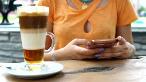 4k joven atractiva usando su teléfono y bebiendo de una taza de café en una cafetería
