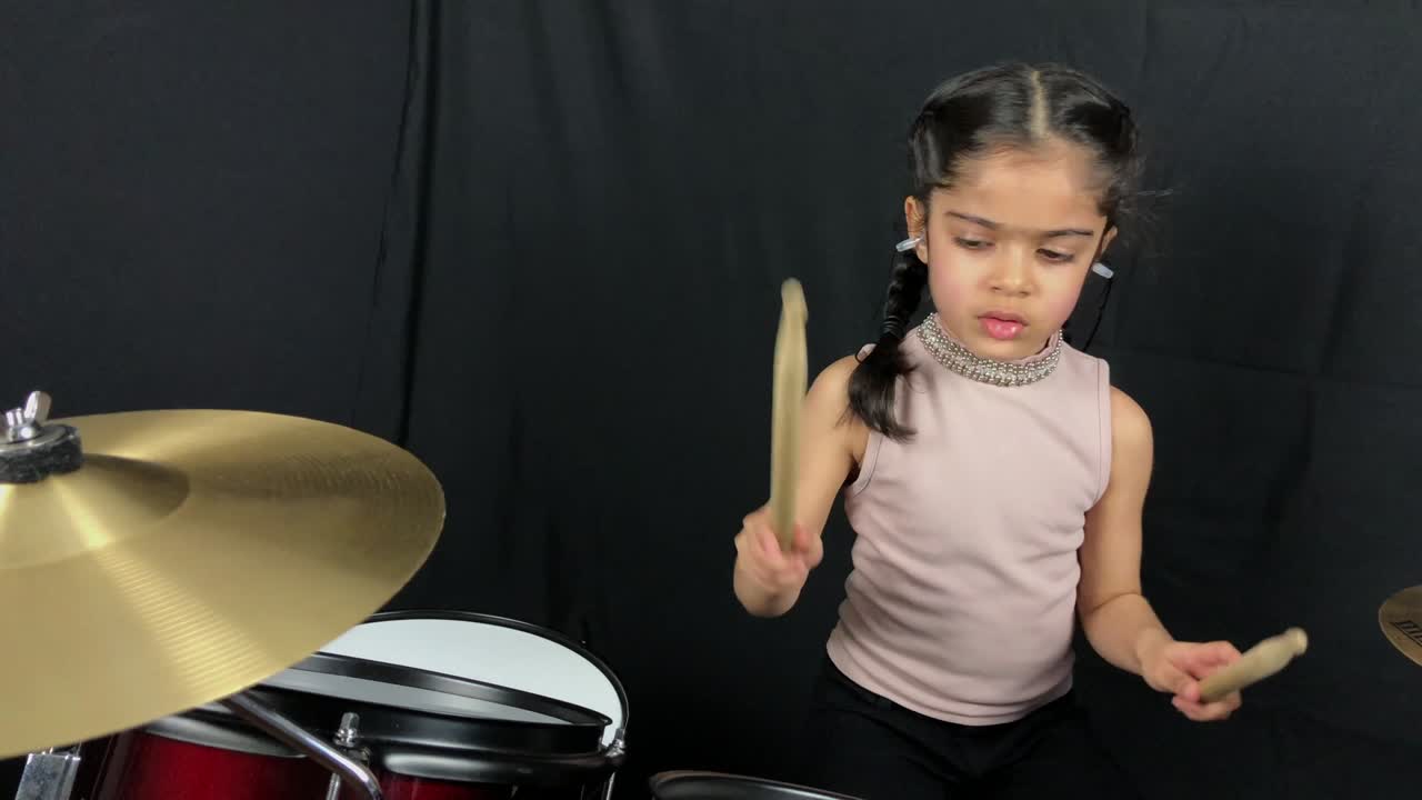 una niña de 5 años practicando la batería.