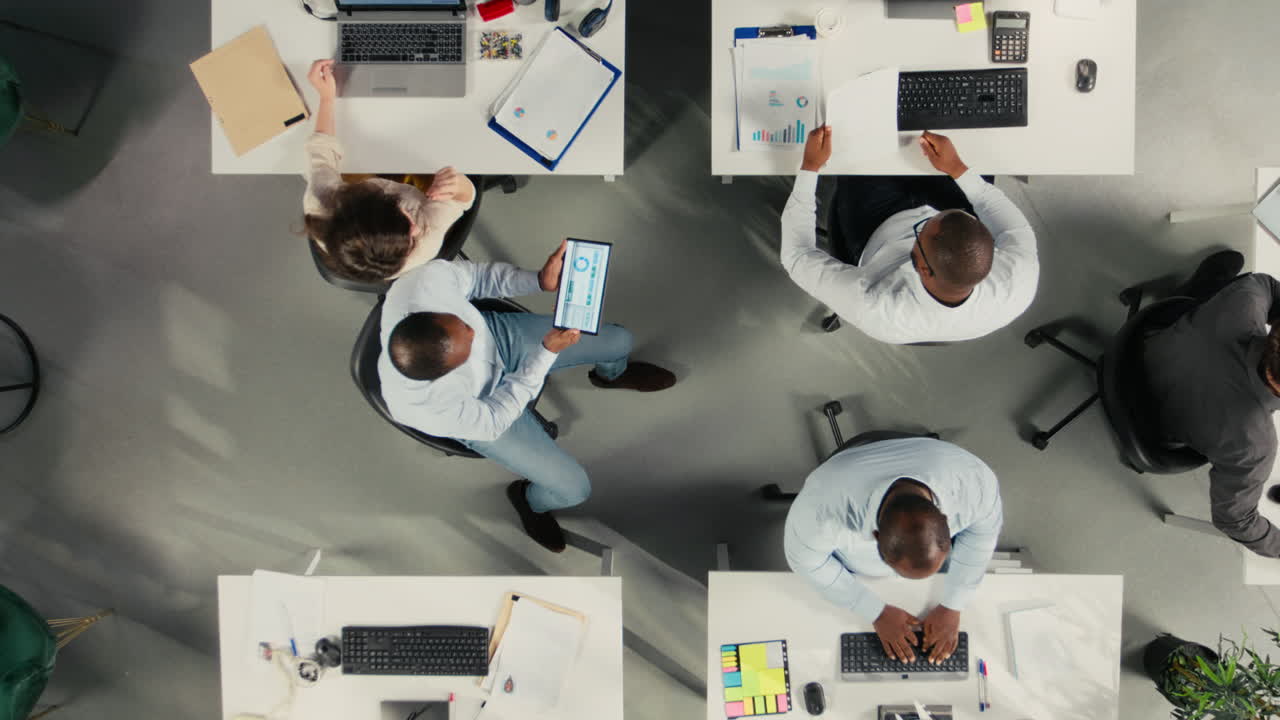 Top down view zoom out of coworkers analyzing business data and metrics