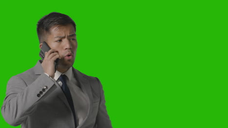 Studio-Shot-Of-Angry-Businessman-In-Suit-Talking-On-Mobile-Phone-Against-Green-Screen-