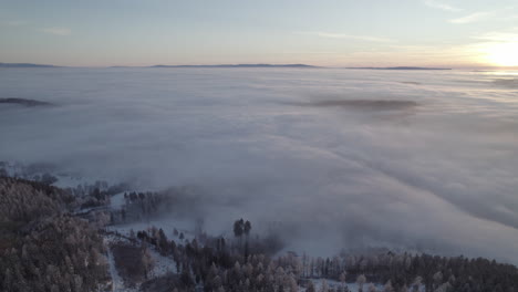 Un-Panorama-En-El-Paisaje-Invernal-Durante-La-Puesta-De-Sol-Con-Una-Densa-Niebla-Que-Cubre-El-Campo-Y-La-Colina-Alrededor