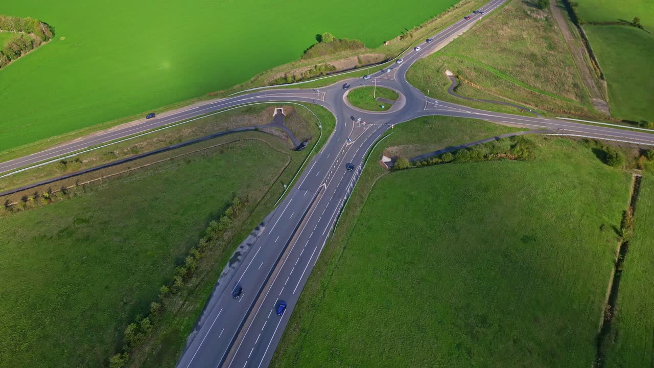 Roundabout intersection with 4 converging roads and green areas, aerial