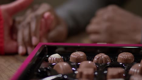 caja de chocolate y pareja tomados de la mano